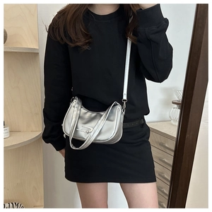 Mirror selfie showing the silver semi-moon crossbody bag with star-shaped hardware detail