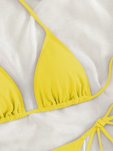 Detail of yellow ribbed bikini top with triangle cups and pleated hem on white fabric