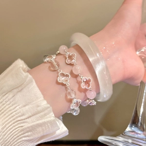 Detail of pink and white crystal bead bracelets with clover charm on a woman's wrist