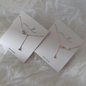 Detail of minimalist 925 silver Y-shape necklaces with pearl and metallic ring accents