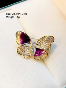 Detailed macro shot of a golden butterfly brooch with purple enamel and tiny crystals