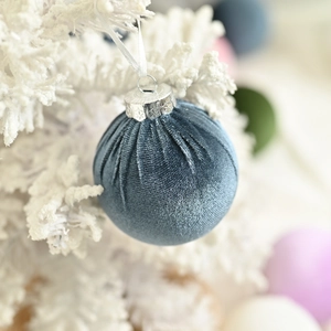 Blue velvet Christmas ball with silver cap hanging on a flocked tree for holiday decoration