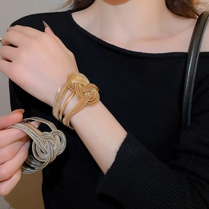 Detail of twisted metal chain cuff bracelet in gold and silver finish on wrist