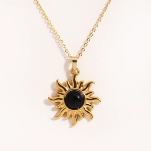 Collana con ciondolo a sole dorato e gemma nera centrale su catena sottile dorata