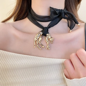 Detail of fabric ribbon choker with a leopard pendant featuring golden finish and spots