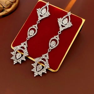 Detailed close-up of silver water drop tassel earrings with sparkling rhinestones on red velvet
