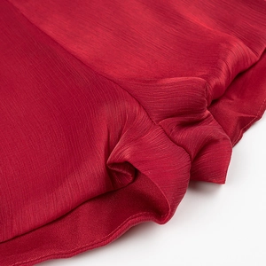 Close-up of dark red pleated fabric texture on the hem of a stylish dress and shorts set