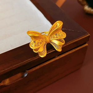 Macro shot of gold butterfly hollow ring with filigree detail on a vintage wood box