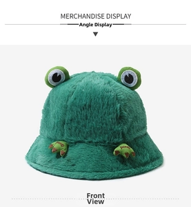 Front view of green plush frog bucket hat with big eyes and 'Good' embroidery
