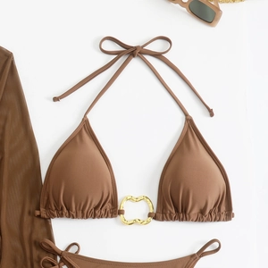 Detailed flat lay of brown bikini top with central gold heart-shaped metal ring detail