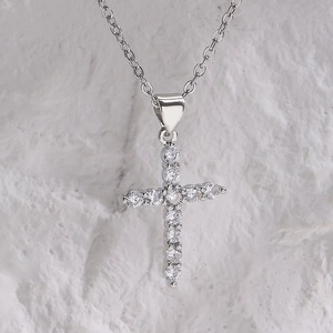 Macro shot of silver cross pendant with micro-inset zircons on a textured surface