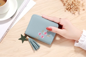 Detail of mint green leather wallet with cherry blossom embroidery and tassel charm