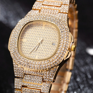 Macro shot of gold tone luxury watch showing date display and iced out diamond bezel