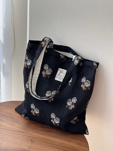 Close-up of black floral jacquard fabric and white rose pattern on a tote bag