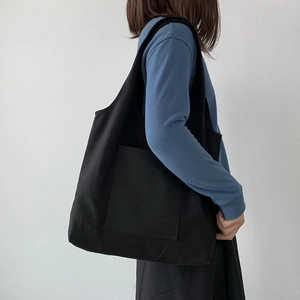 Side view of a black canvas tote bag with large capacity and front pocket for women