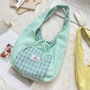 Close-up detail of mint green plaid vest bag showing the bow tie closure and fabric texture