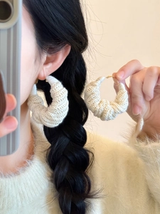Vue détaillée de boucles d'oreilles en laine blanche tricotée avec fermoir doré d'hiver