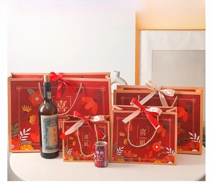 Detail of red floral wedding gift bags in four sizes with gold woven rope handles
