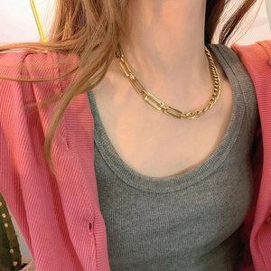Detail of half-link and half-Cuban chain gold necklace worn on a model's neck