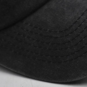 Close-up of curved stitching details on the brim of a black washed cotton baseball cap
