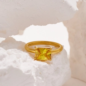 Detail of 18K gold plated titanium ring with square yellow gemstone on white stones