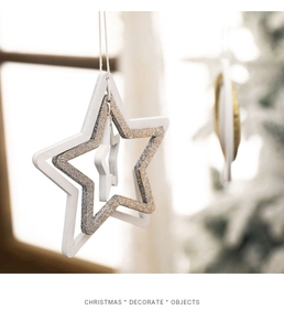 Macro shot of white wooden star ornaments with gold and silver glitter on Christmas tree