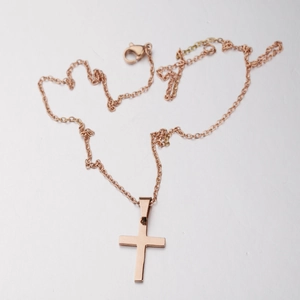 Macro view of polished rose gold cross pendant necklace with smooth mirror finish