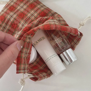 Detail of red and green plaid drawstring storage pouch with skincare items inside