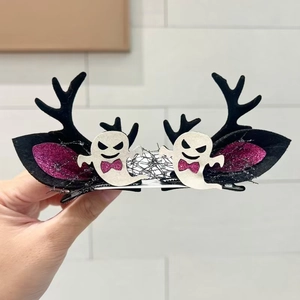 Detail of Halloween hair clips with glitter bat wings and ghost elements held in hand