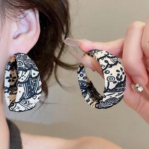 Détail de la boucle d'oreille créole en tissu avec broderie graffiti noir et blanc et métal doré