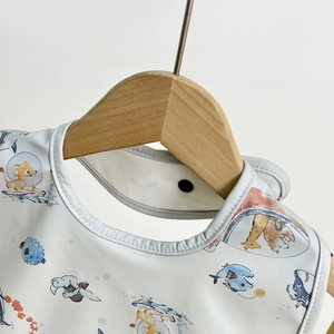Detail of waterproof baby bib featuring cute animal astronaut prints and snap fastener