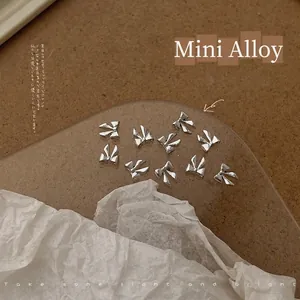 Detailed macro view of 5x5.5mm silver alloy bow nail charms for DIY manicure art