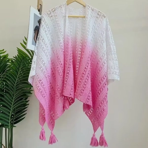 Close-up of crochet knit texture with pink gradient and fringe tassels on the shawl