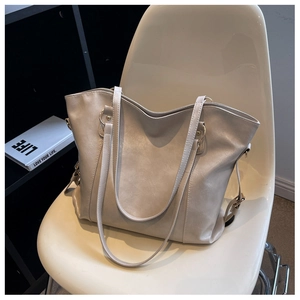 Detailed view of a minimalist cream-colored large capacity PU leather tote bag on a chair