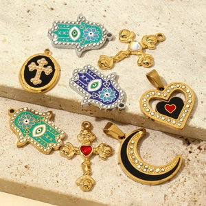 Assorted stainless steel charms including Hand of Fatima and cross on stone background