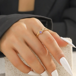Detail eines goldenen Herzrings mit violettem Stein und Zirkon an der Hand eines Modells