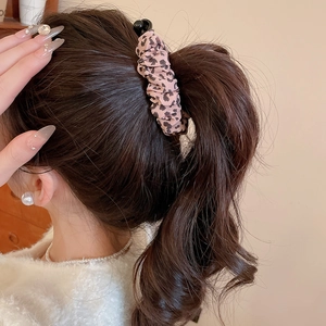 Detail view of a leopard print fabric hair clip styled on a brunette high ponytail