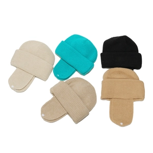 Flat lay of five-color knitted winter hats with earflaps and decorative white buttons