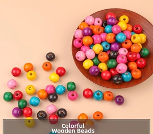 Perline tonde in legno d'acero colorate con fori per gioielli fai-da-te su un piatto di legno