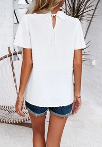 Detail of white short sleeve top with textured dots and lace-up back design
