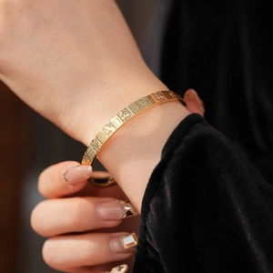 Close-up of a minimalist gold bracelet featuring a mahjong texture and geometric patterns