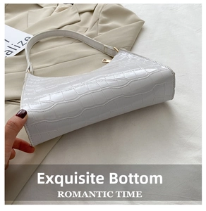 Detail shot of white crocodile pattern underarm bag with gold zipper on beige blazer