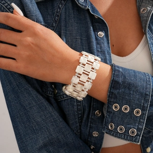 Close-up of a silver-toned wide metal bracelet with three rows of textured square plates