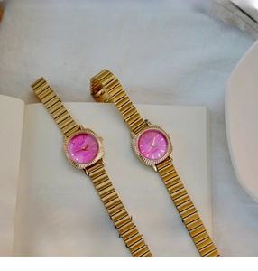 Detailed view of two vintage gold watches with pink dials on a classic English book