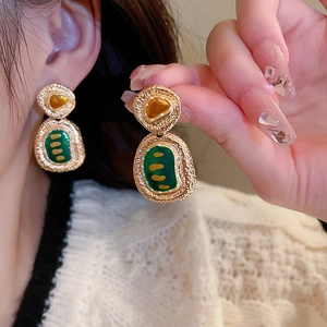Macro view of vintage gold flower earrings with amber gemstones and green oil painting texture
