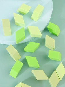 Macro shot of colorful diamond-shaped makeup sponges on a soft pastel background