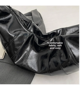 Detail shot of black glossy pleated dumpling bag featuring high-shine textured finish