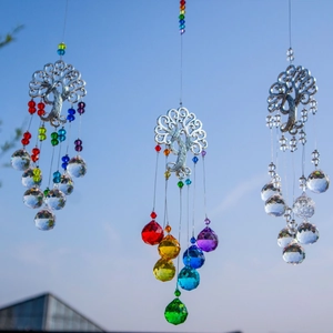 Three tree of life suncatchers with colorful crystal prisms hanging under blue sky