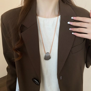 Detail of silver shell pendant with intricate texture on an orange cord necklace