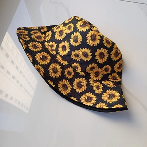 Outdoor sun protection bucket hat with sunflower print on black fabric, 45-degree angle view